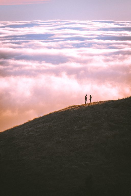 couple standing in a field on a mountain