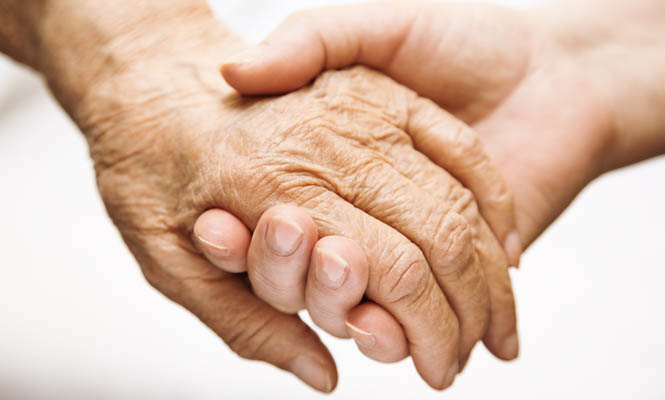 caregiver holding the hand of terminally ill patient