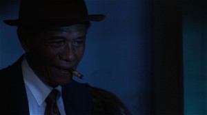 Anwar smoking a cigar dressed as a 1920s American gangster