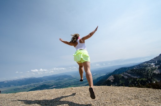 A woman running with her arms spread out to her side along the edge of a cliff