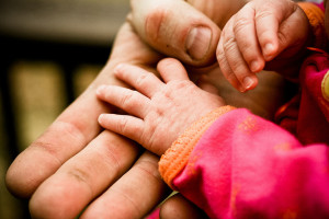 A man holding a newborn baby's hand
