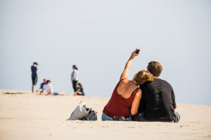 A couple taking a selfie with a phone on the beach