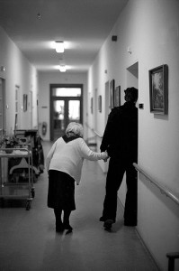 An old woman walking down the hallway of a nursing home