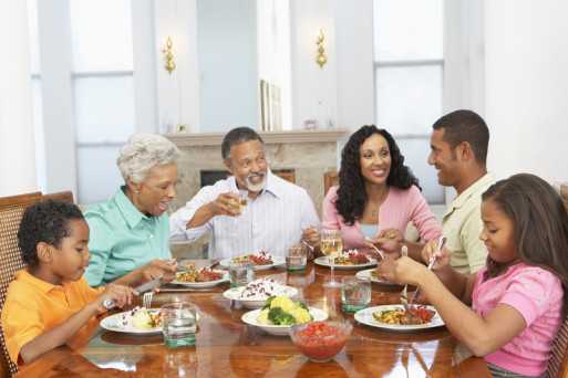 A multi-generational family smiles over supper table conversation about estate planning
