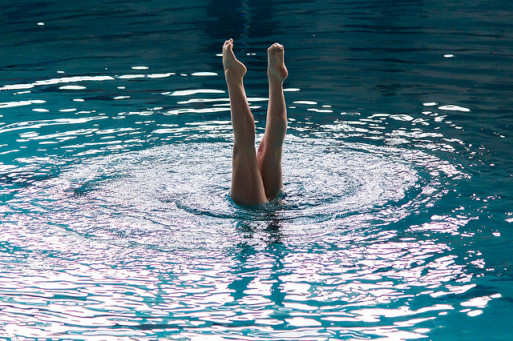 A synchronized swimmer putting her legs in the air in the water