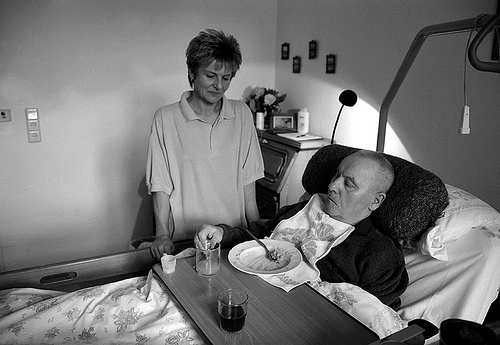 A woman standing next to a man's bedside
