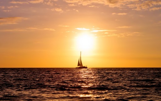 boat sails away into the distant sunset