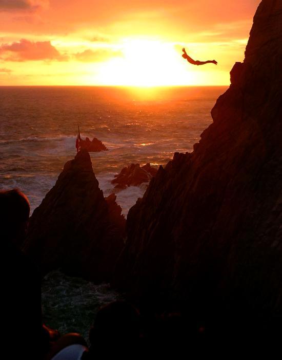 man cliff diving at sunset to live a wild life
