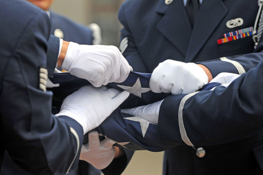 Military members fold an American flag at a funeral