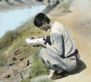 A man sitting on a river bank reading a letter