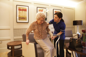 Elderly woman in an assisted living facility being helped into a chair