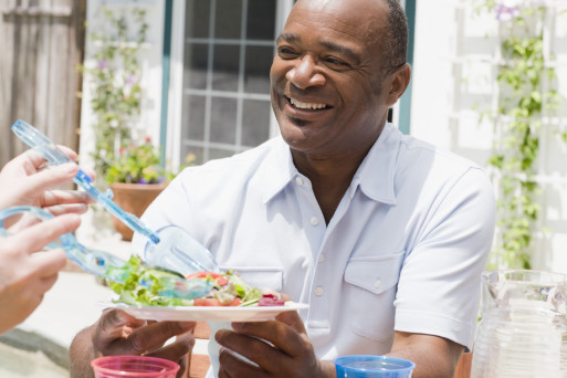 A fit African American middle aged man being served a healthy salad