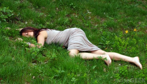 A woman lying down in the grass as if in death