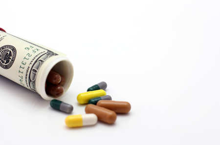 Pills falling out of a rolled up bill shows cost of health care for the terminally ill