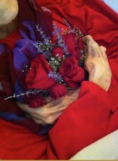 hands of a dead loved one holding flowers at a home funeral