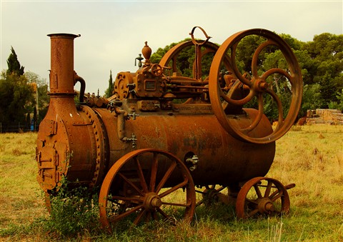 A rusted machine in a field where a dog is buried
