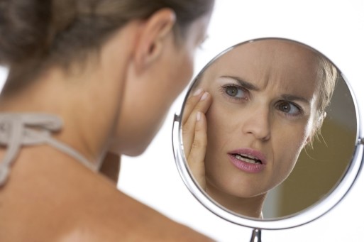 Woman looking in the mirror afraid of aging