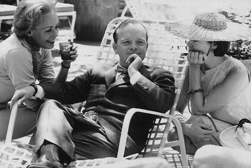 A black and white photo of author Truman Capote, enjoying life with two women friends