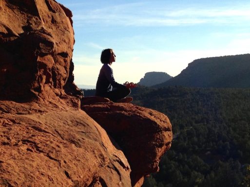 A woman meditates about life and death while she sits on a cliff ledge