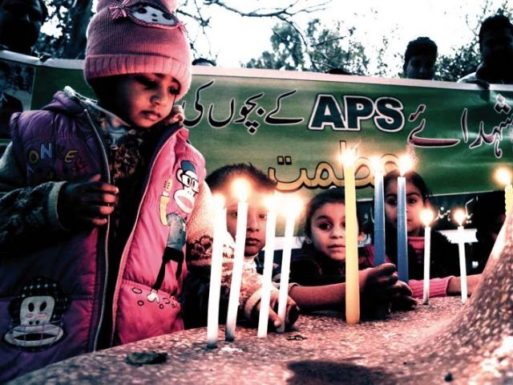 Children light candles at a memorial 