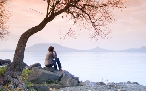 A woman looking out over a lake remembering a loved one who has died