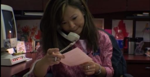 A woman holds a phone to her ear and looks at a piece of paper in this screenshot from the documentary about death and dying