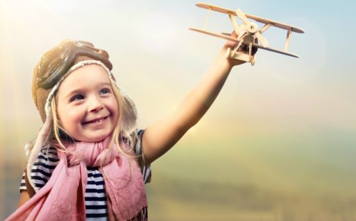 Little girl flying an wooden airplane enjoying life from the start