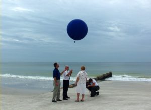 Family on a beach releasing a balloon containing loved one's cremains