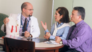 A doctor speaks with two patients about their medical intervention options