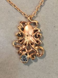 A diamond memorial piece featuring a gold necklace shaped like an octopus, holding a small diamond