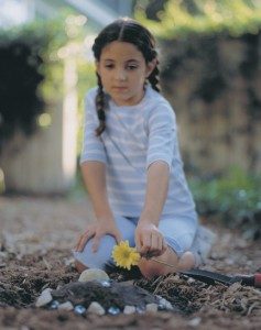 Child placing flowers on a grave after a home funeral