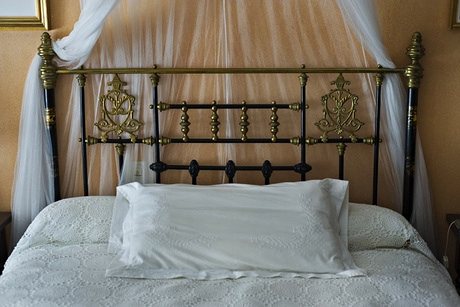 Beatriz Ruibal's photograph of her mother's bed, with white lace sheets, a gold metal headboard and a white organza decorative net