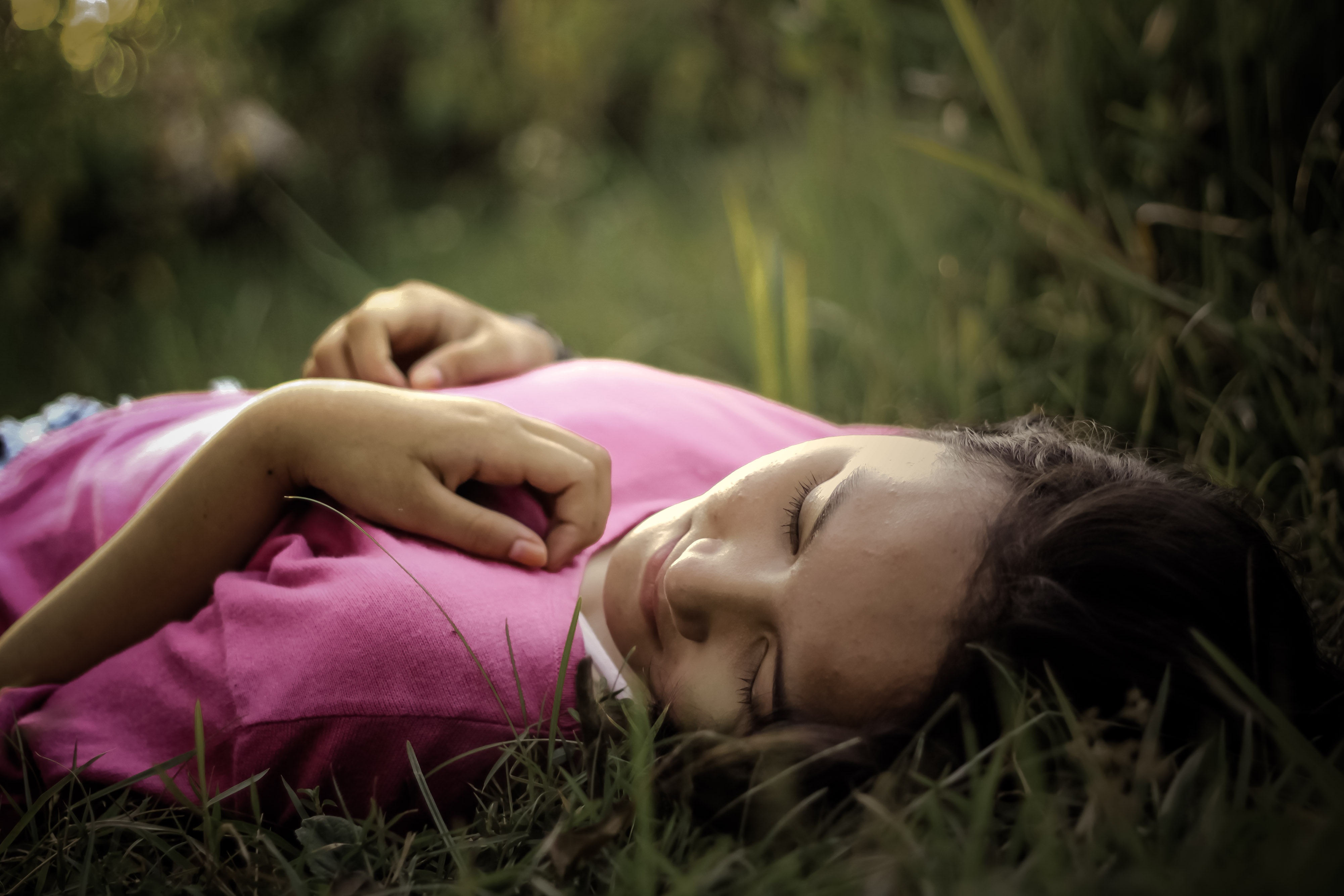 A woman lies in the grass with her eyes closed peacefully, as described in this Oscar Wilde quote