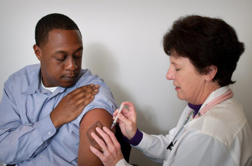 A black patient receives a shot in a hospital as part of palliative care