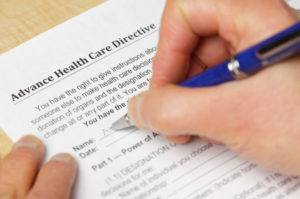 A person filling out a form titled Advance Directive and a pen. 