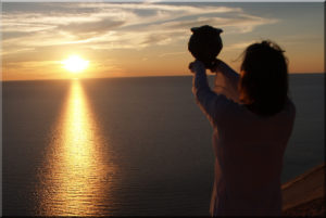 Woman holding a cremation urn into the sunset