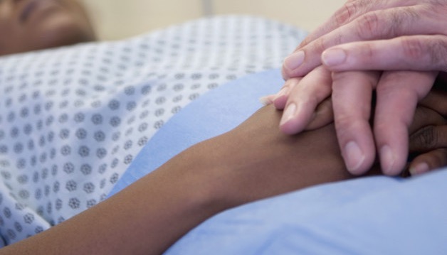 A son holds the hand of his dying father, remembering the living years
