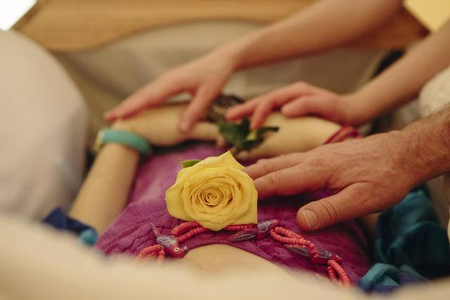 Family touches a loved one after death as celebrant looks on