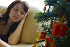 Young woman sitting on a couch looking sad during the holidays