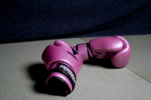 A pair of boxing gloves sitting on the floor, symbolizing fighting death