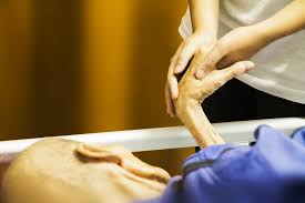 A caregiver holds a hospice patient's hand while the patient lies in bed dying, not fighting death