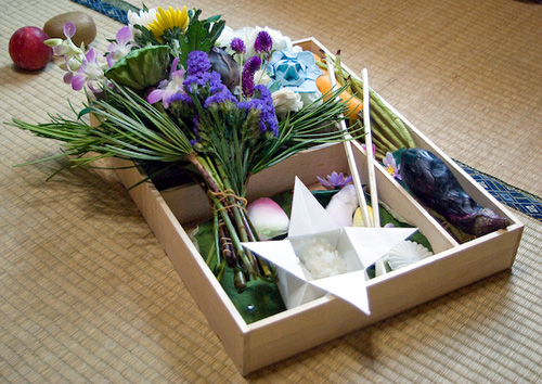 flowers and origami in a wooden box are part of a Japanese funeral ceremony