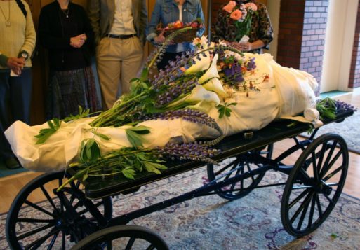 A shrouded body covered with flowers during celebrant ritual