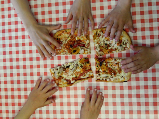 Three people pass four slices of pizza to each other