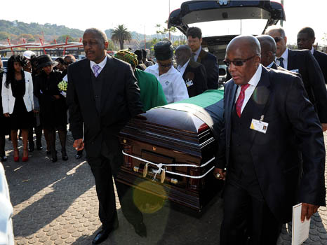 Two men help carry a coffin out of a car in South Africa in a solemn ritual unlike after-tears parties