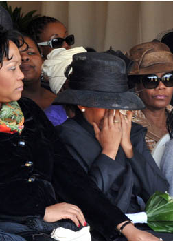 A widow cries into her hands at her husband's funeral in South Africa 