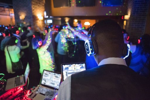A DJ wearing headphones plays music for a crowd of young people at an after-tears party