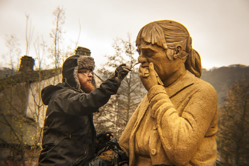 A Sand In Your Eye artist adds details to the sand sculpture's face, a grieving woman