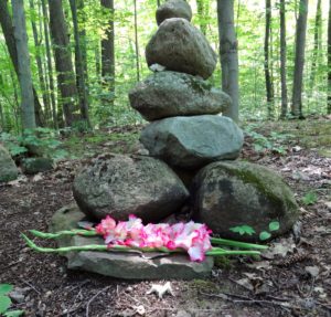 rocks placed in a forest with flowers for grief ritual