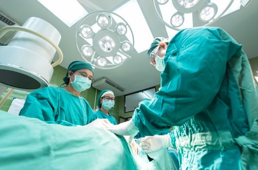 A group of three doctors perform surgery on a patient in an operating room